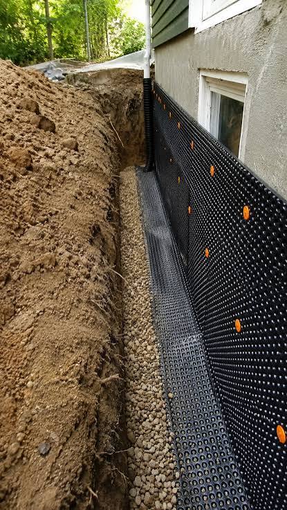 Foundation waterproofing membrane installed along an excavated foundation wall with drainage gravel